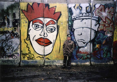Ein Grenzsoldat steht vor Mauerresten mit Graffiti
