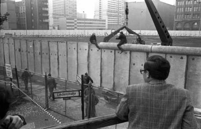 Besucher einer Aussichtsplattform beobachten auf das Anbringen der Rohrauflage auf die Grenzmauer 75 an der Zimmerstraße