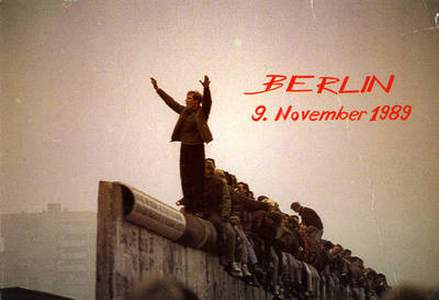 Sitzend und stehende Menschen auf der Krone der Berliner Mauer;