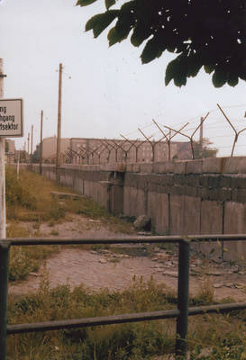 Überwucherter, zu Ost-Berlin gehörender Bürgersteig vor Betonverbundmauer