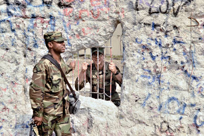 Zwei amerikanische Soldaten vor und hinter einer Mauerlücke in der Zimmerstraße